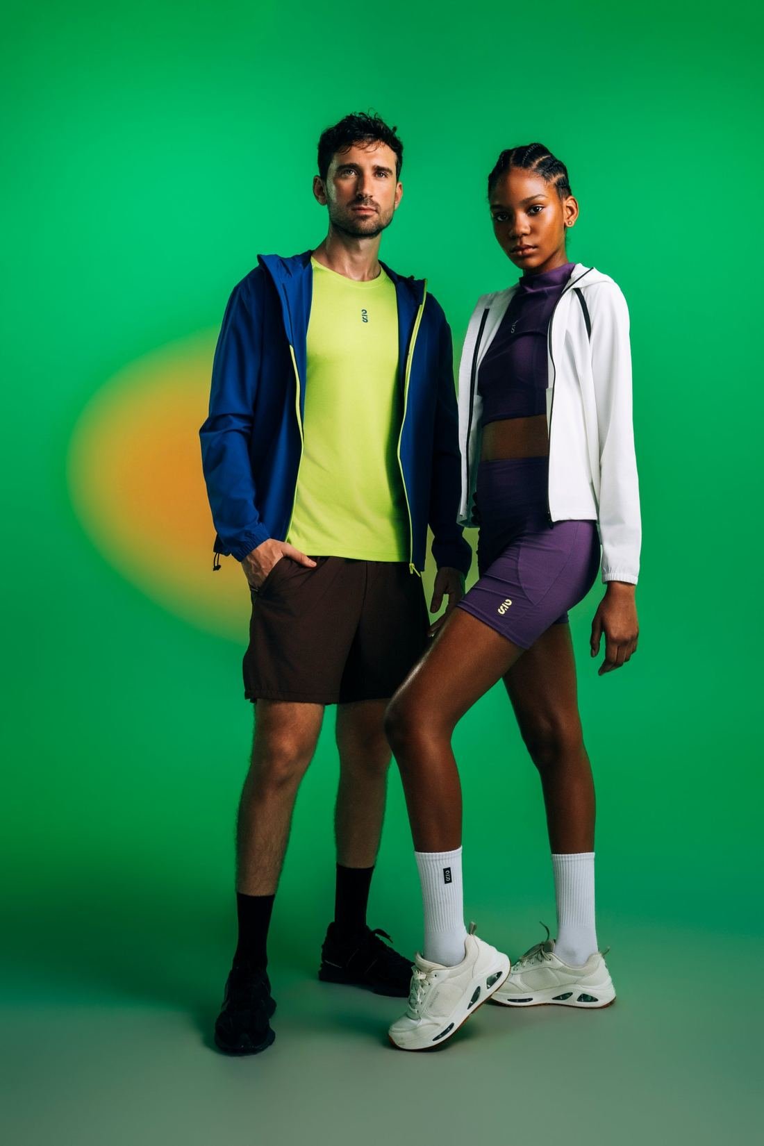 Dos modelos con chaquetas, tops y shorts 2S sobre fondo verde
