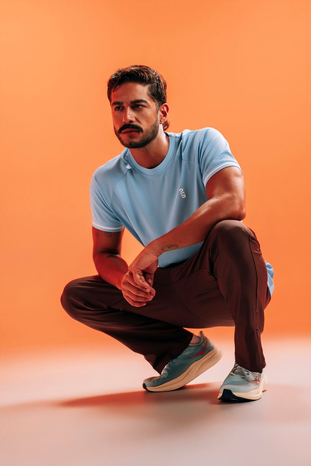 Modelo con camiseta azul y pantalón 2S sobre fondo naranja